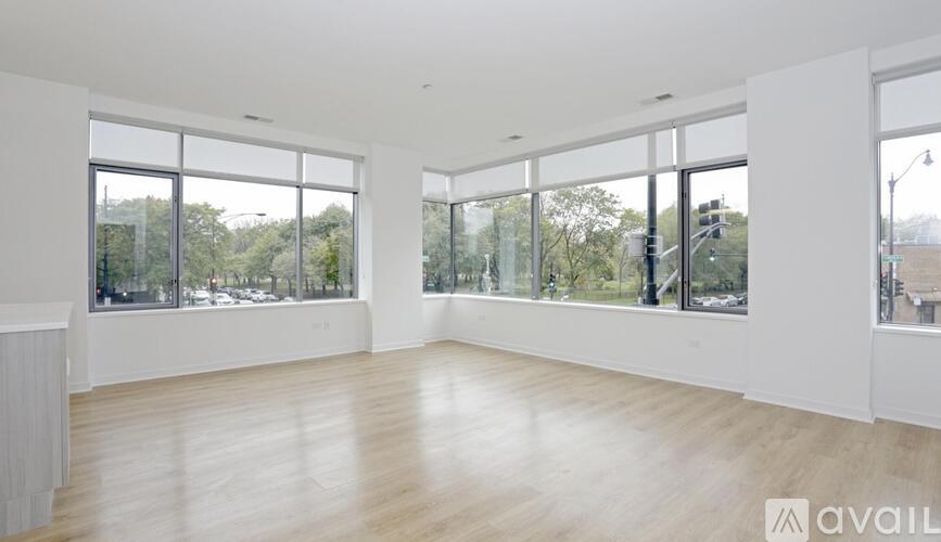 A spacious room with large windows and wooden flooring.