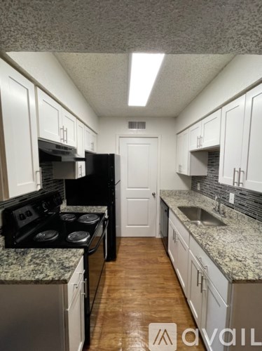 A kitchen with white cabinets and a granite countertop.