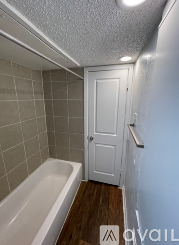 A white door is in a bathroom with a white bathtub.