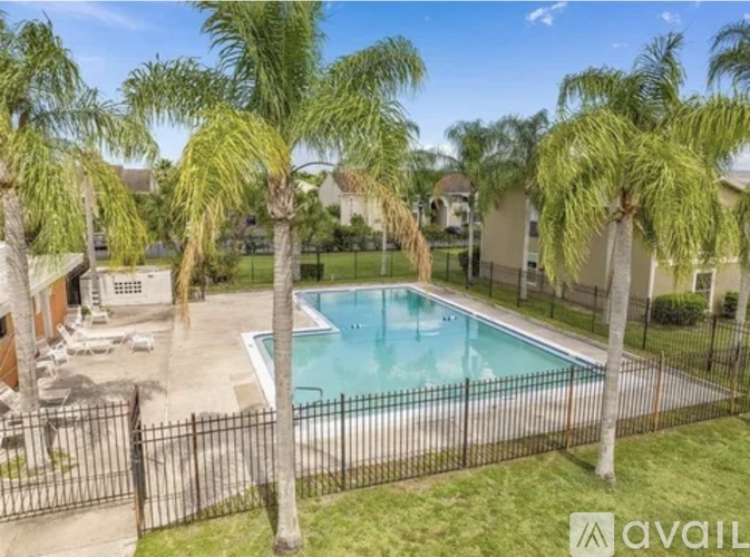 A pool surrounded by a black fence and palm trees.