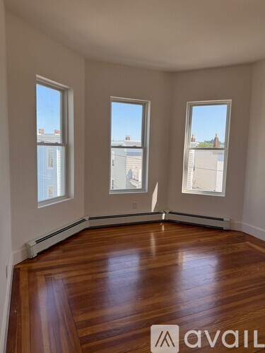 A room with wooden floors and three windows.