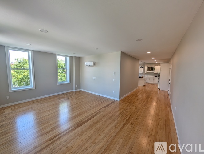 A spacious room with wooden flooring and large windows.