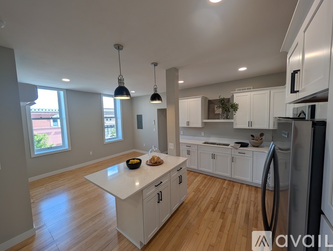 A modern kitchen with white cabinets and a wooden floor.