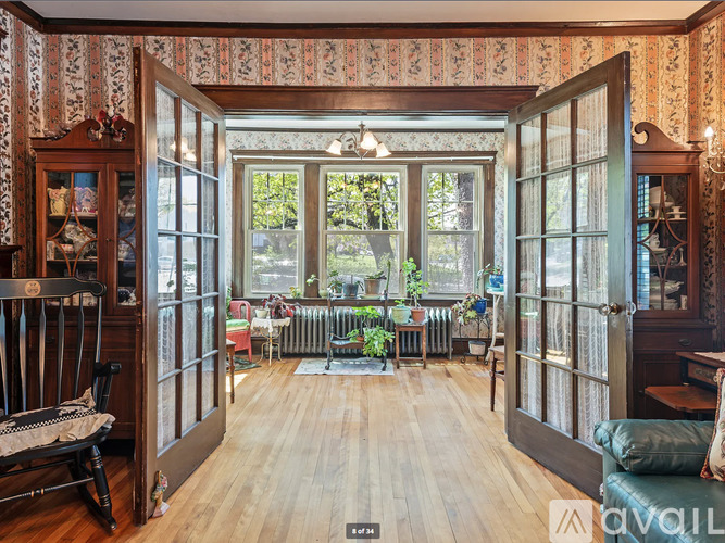 A room with a wooden floor and a large window with a view of trees.
