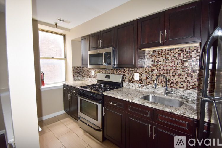 A kitchen with dark wood cabinets and a granite counter top.