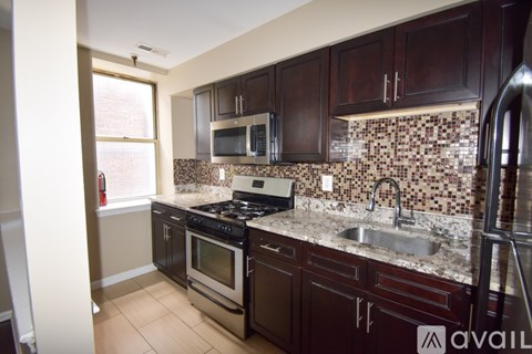 A kitchen with dark wood cabinets and a granite counter top.
