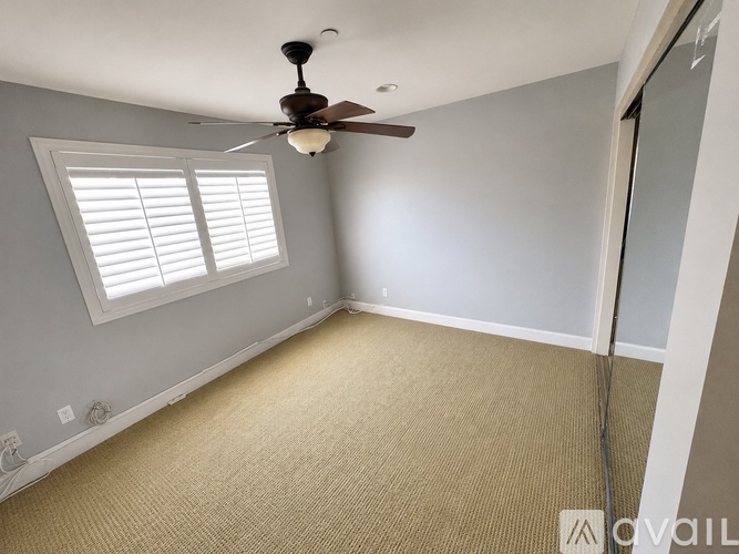 A room with a ceiling fan and a window with blinds.