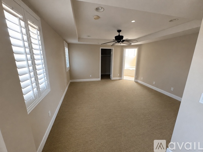 A spacious room with a ceiling fan and carpeted floor.