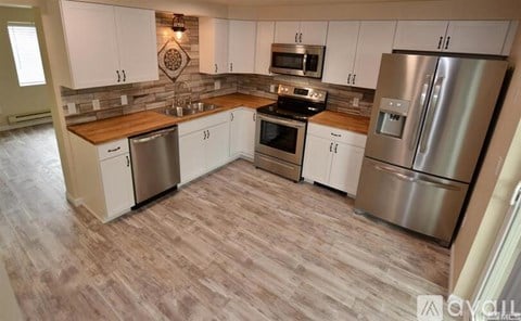 A kitchen with white cabinets and a wooden counter top.