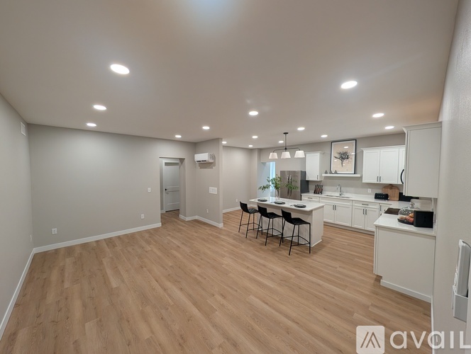 A spacious kitchen and dining area with wooden flooring and white walls.