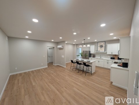 A spacious kitchen and dining area with wooden flooring and white walls.