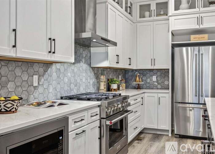 A kitchen with white cabinets and a stainless steel refrigerator.