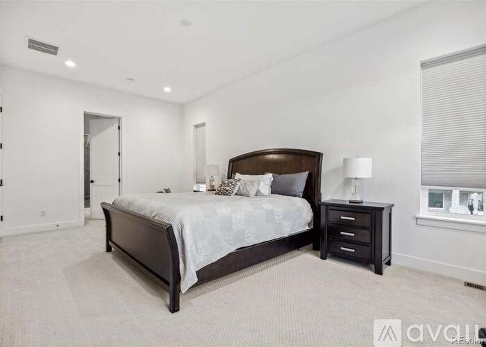 A bedroom with a large bed, nightstand, and window.