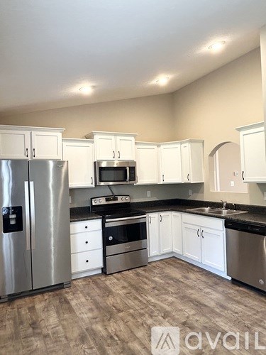 A kitchen with white cabinets and a stainless steel refrigerator.
