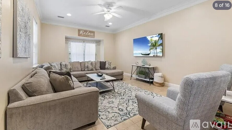 A living room with a couch, chair, and a flat screen TV mounted on the wall.
