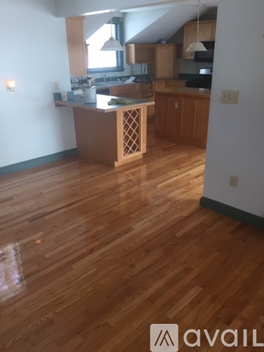 A kitchen with wooden floors and a white wall.