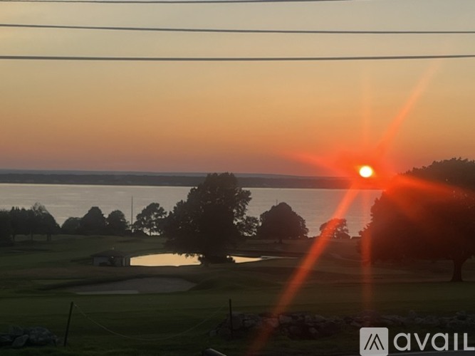 The sun is setting over a golf course with a lake in the background.