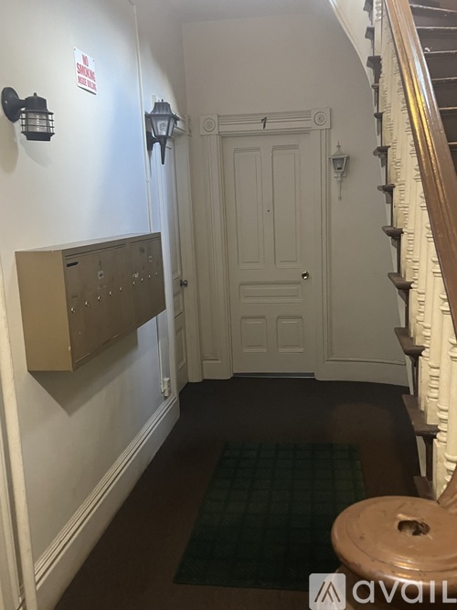 A hallway with a white door and a brown mat on the floor.