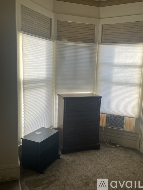 A room with a black chest of drawers and a small black box.