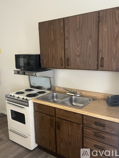 A kitchen with a white stove and wooden cabinets.