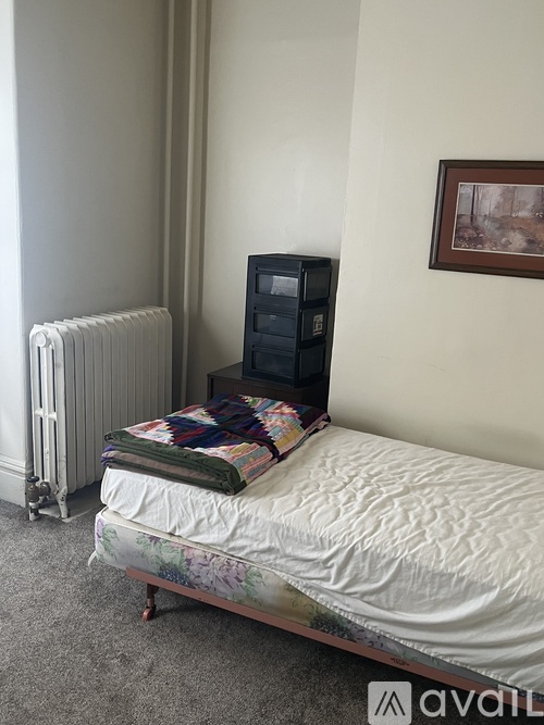 A bed with a white sheet and a black computer on top of it.