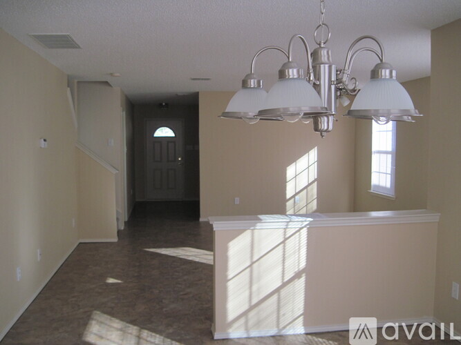 A large empty room with a chandelier and a window.