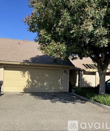 A house with a garage door and a tree in front.