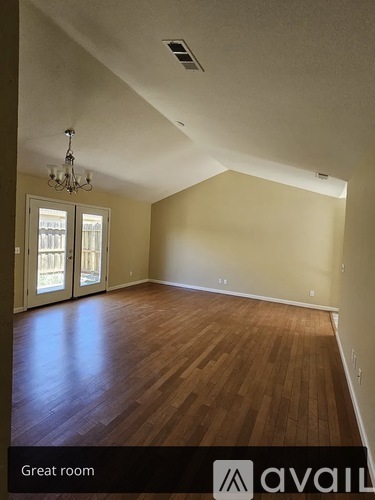 A large empty room with wooden floors and a chandelier.