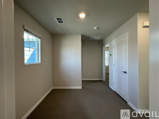 A room with a carpeted floor, a window, and a door.