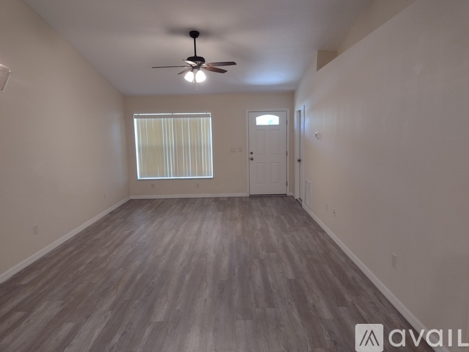 A room with a ceiling fan and wooden flooring.