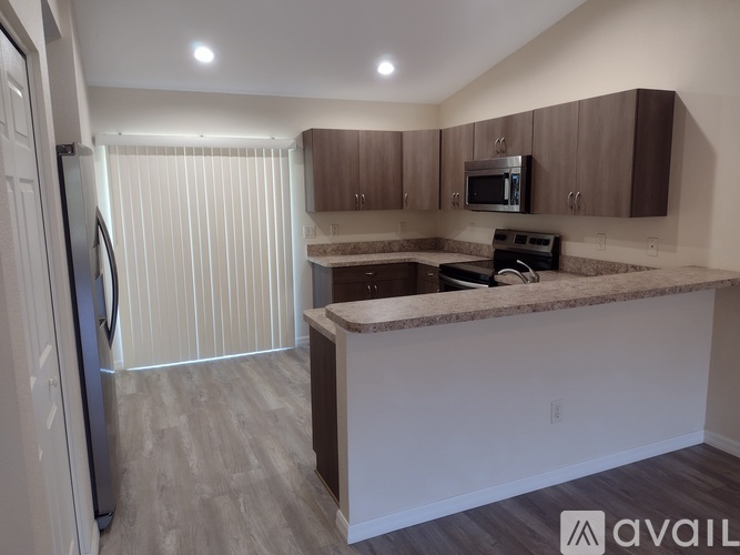 A kitchen with a refrigerator, microwave, and oven.