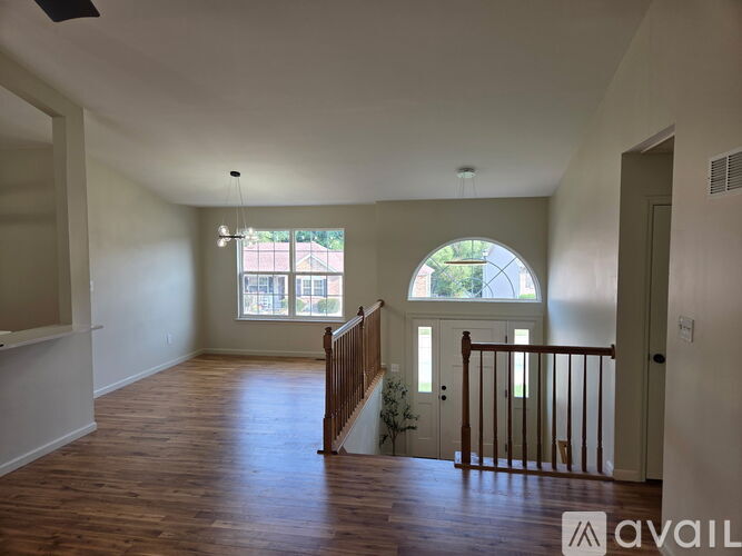 A spacious room with wooden floors and a staircase leading to the second floor.