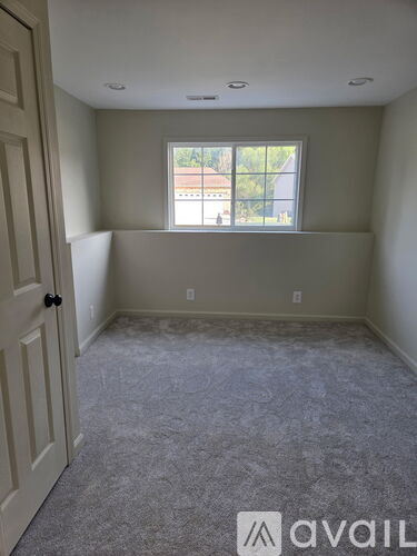 A room with a carpeted floor and a window showing a view of a building outside.