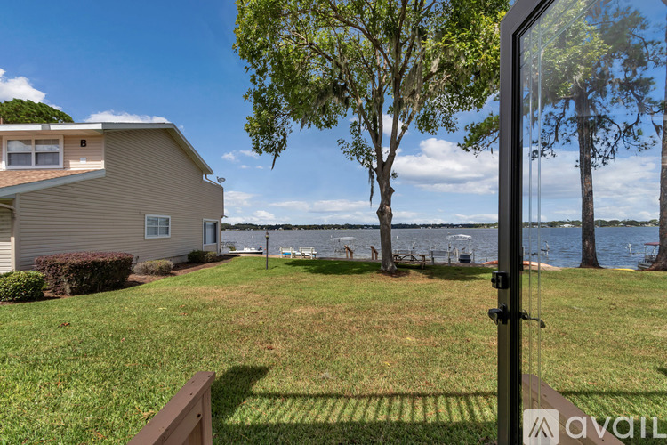 A house with a lawn and a tree in front of a body of water.