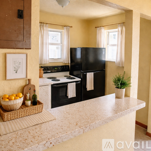 A kitchen with black appliances and a basket of fruit on the counter.