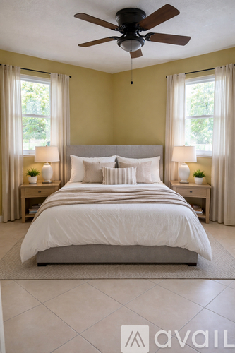 A bedroom with a large bed and a ceiling fan.
