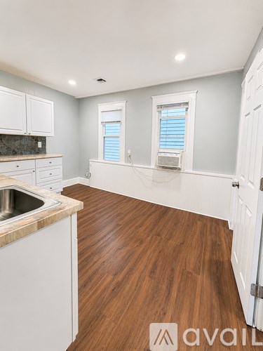 A kitchen with white cabinets and a wooden floor.