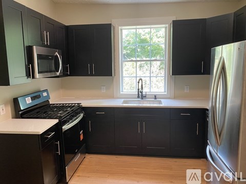 A kitchen with black cabinets and a stainless steel refrigerator.