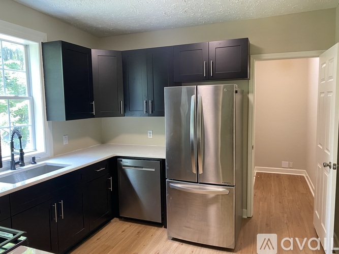 A kitchen with a refrigerator, sink, and cabinets.