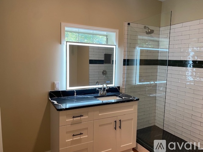 A bathroom with a sink, mirror, and a shower.