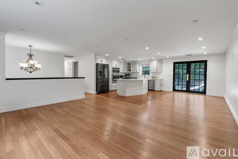 A spacious room with wooden flooring and a chandelier hanging from the ceiling.