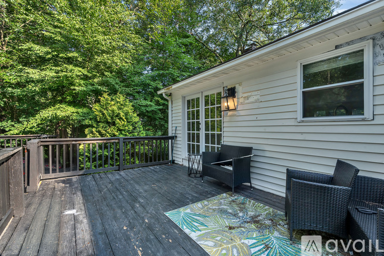 A deck with a table and chairs is surrounded by trees.