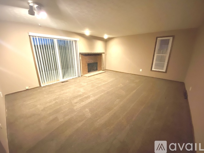 A room with wooden flooring and a window with blinds.
