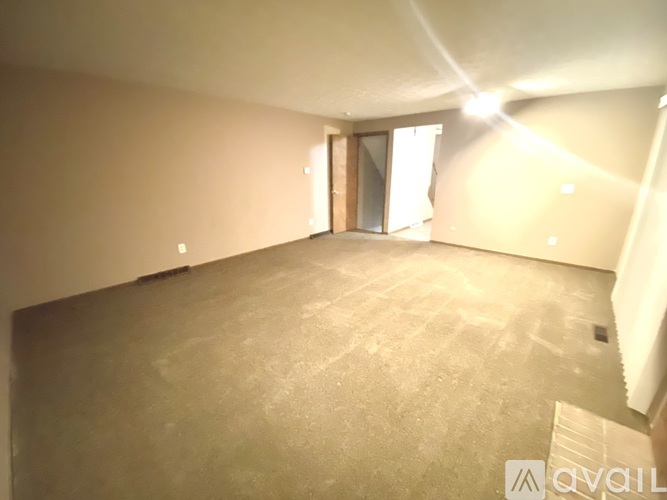 A spacious room with a carpeted floor and a door on the right side.