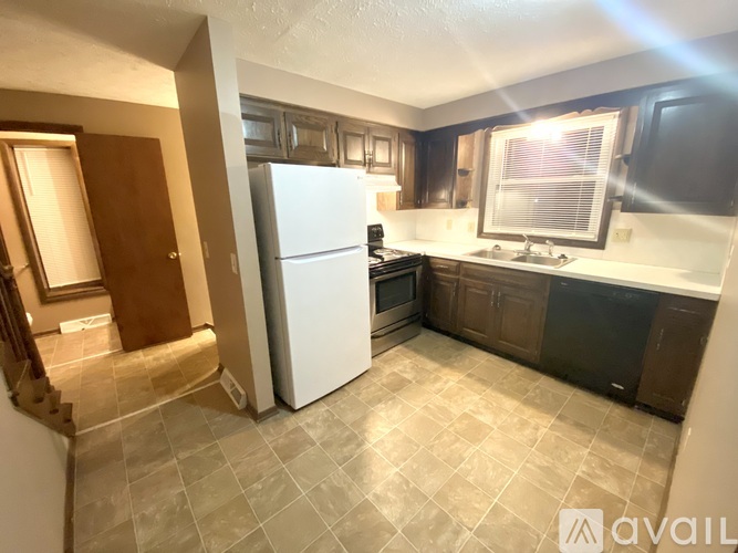 A kitchen with a white refrigerator and brown cabinets.