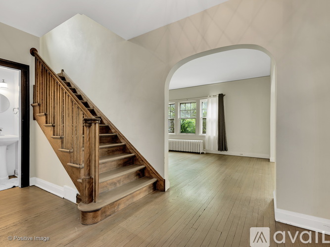 A wooden staircase with a white wall and a window with a view of trees.