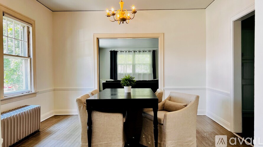A dining room with a table, chairs, and a chandelier.