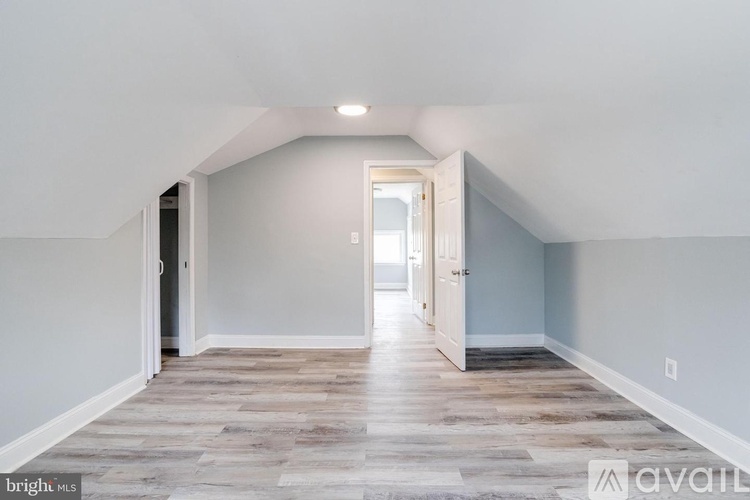 A spacious room with wooden flooring and a white door.
