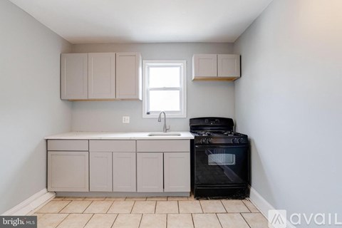 A kitchen with a black oven and a sink with a window above it.