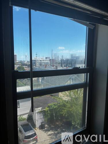 A window with a view of a parking lot and buildings outside.